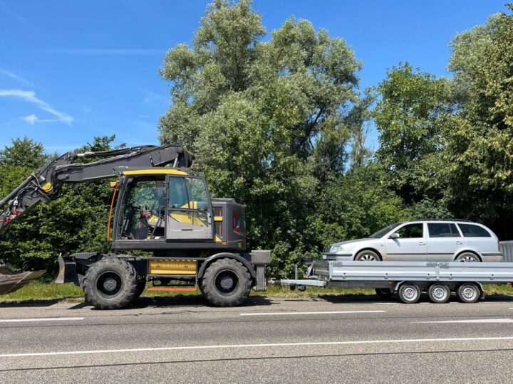 Schaufelbagger zieht Anhänger mit Auto: Polizei stoppt „ungewöhnliches Gespann“ auf der B58