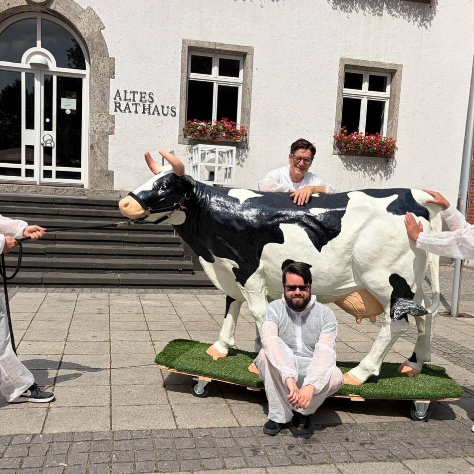 Kuriose Aktion in Grevenbroich: Warum vier Männer mit einer Kuh durch die Stadt ziehen